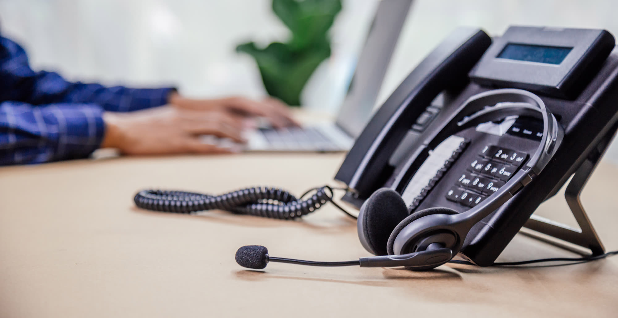 A business desk phone and headset on an office desk
